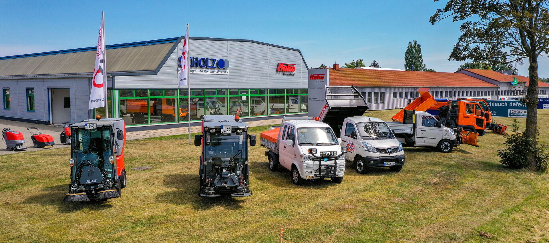 Reihe von Kommunalfahrzeugen und Transportern vor Firmenstandort.